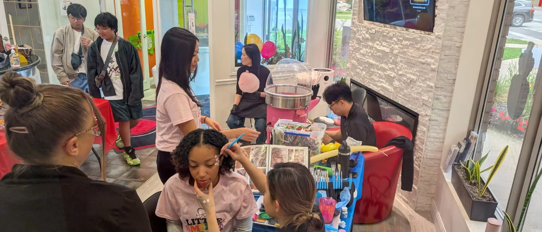 Families and Heartland team members enjoying face painting and cotton candy at the Little Smiles event